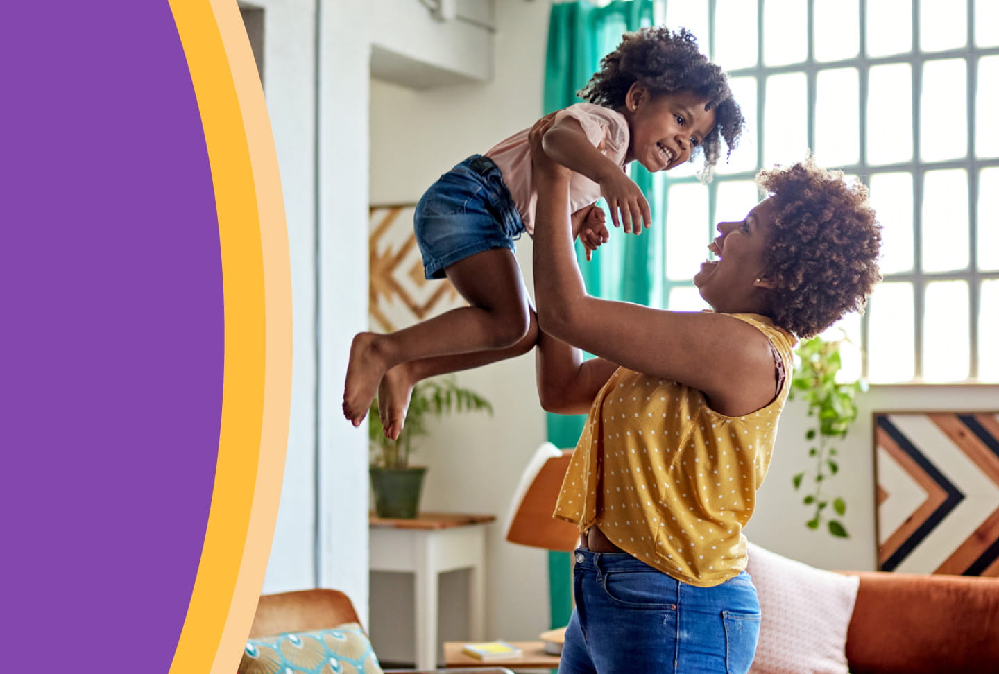 Mother smiling and lifting child up in the air.